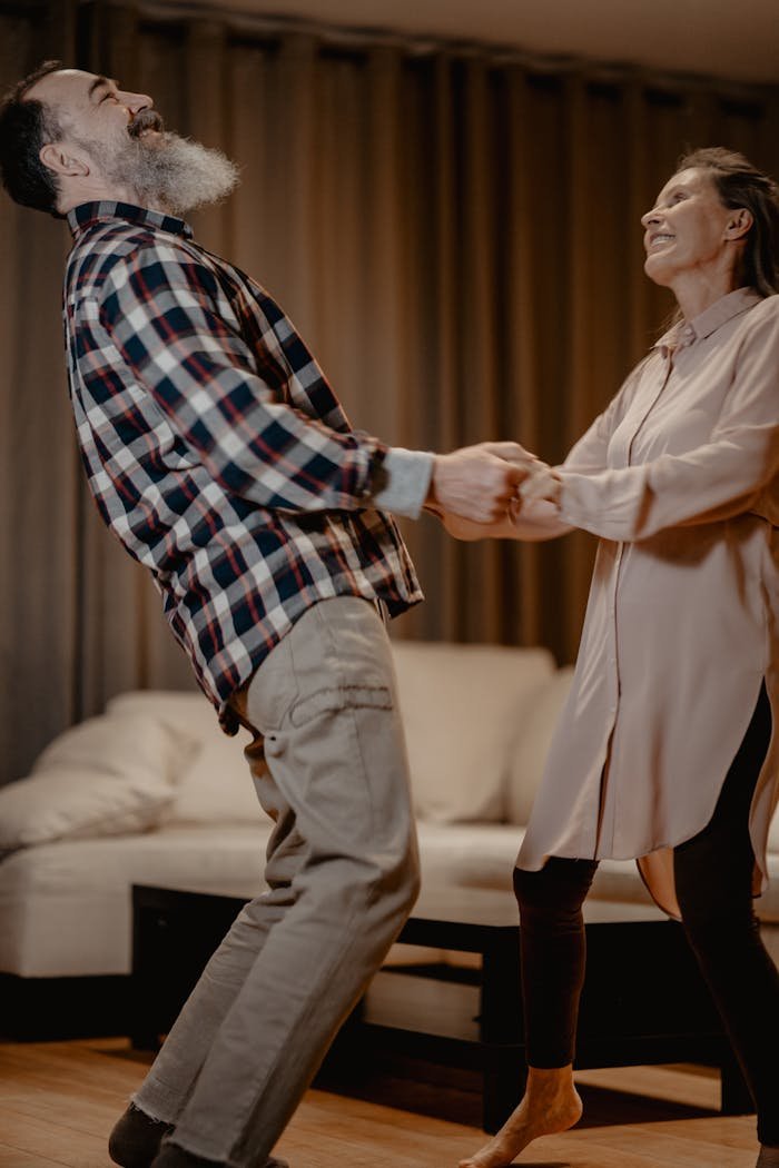 Senior couple dancing joyfully in their cozy living room, showcasing love and happiness.